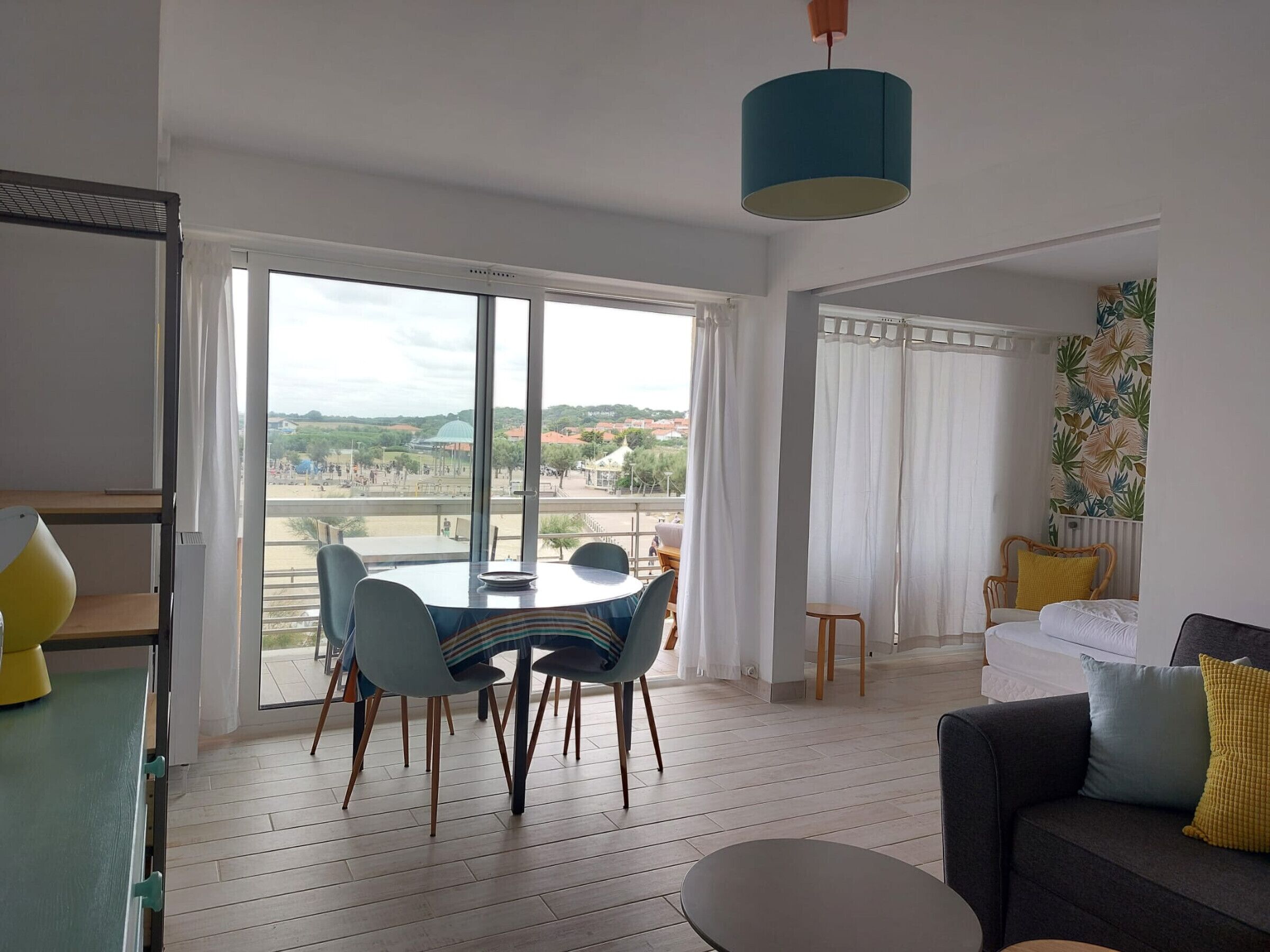 A spacious living area with a dining table and chairs, a sofa, and a view of the outdoors.