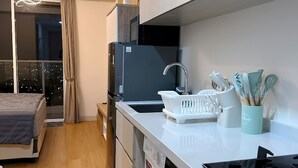 Une cuisine compacte équipée d’un lave-linge, d’un four à micro-ondes et d’un évier.