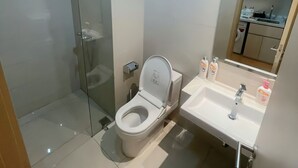 Une salle de bain moderne avec une douche à parois de verre, des toilettes et un lavabo surmonté d’un miroir.