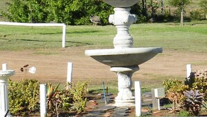 Una fuente de piedra con varios niveles en un jardín ajardinado.