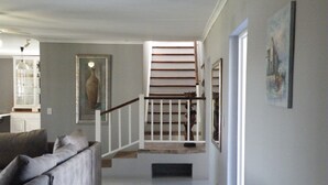 Un pasillo con una escalera, un sofá y obras de arte enmarcadas en las paredes.