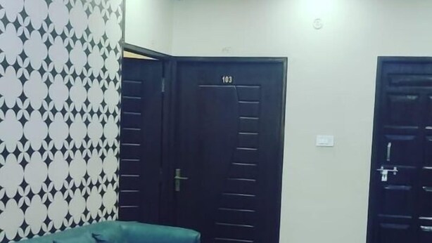Un salon moderne avec un canapé vert, une table basse blanche et un mur orné d’un motif.