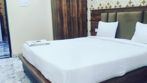 Un lit bien fait, avec du linge de lit blanc, dans une chambre dotée d’une tête de lit en bois et d’une armoire.