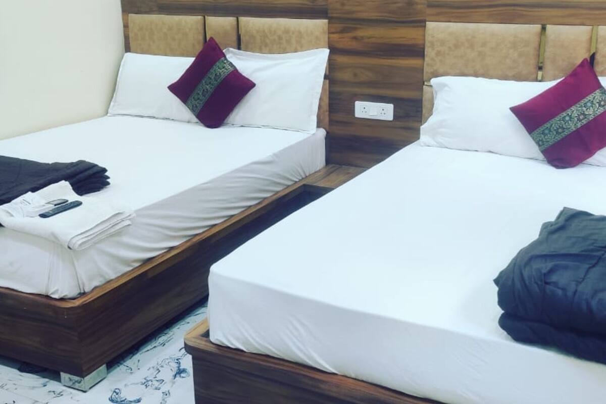 Dos camas individuales con cabeceros de madera, ropa de cama blanca y almohadones decorativos.