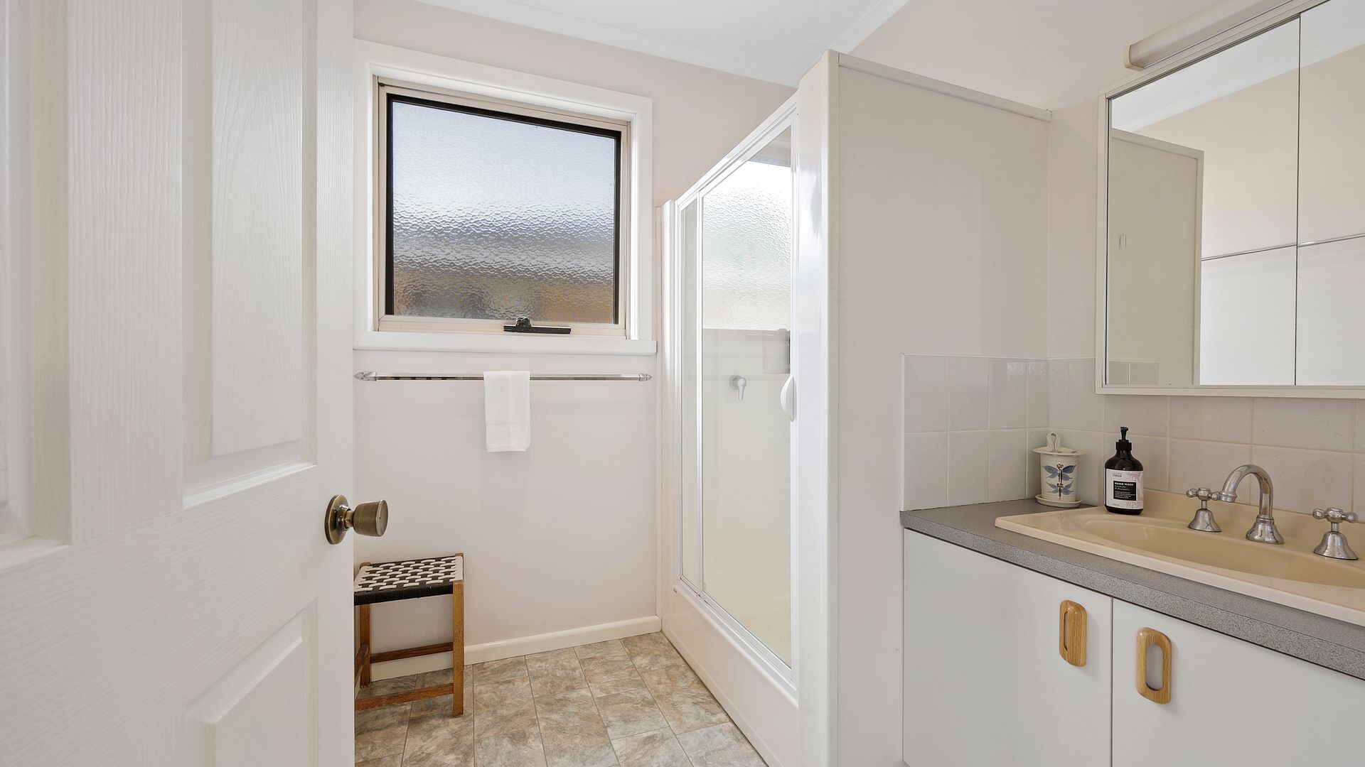 Ein Badezimmer mit Dusche, Waschbecken, Fenster und Handtuchhalter.
