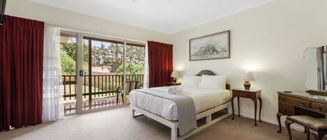 A bedroom with a bed, a nightstand, a dresser, a mirror, and a balcony with red curtains.