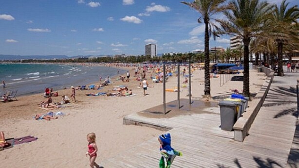 A beach with a wooden boardwalk, palm trees, and a clear blue sky. - Family apartment in Salou with Wi-Fi 300m from the beach (Salou)