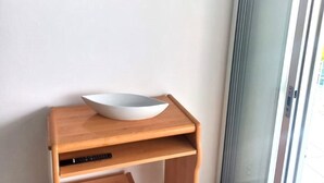 A room with a wooden side table, a white bowl, a remote control, and a TV mounted on the wall. - Family apartment in Salou with Wi-Fi 300m from the beach (Salou)