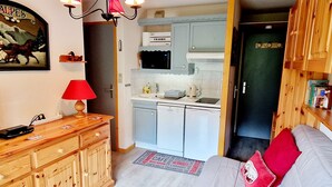 A compact kitchen with a microwave, kettle, and toaster. A wooden cabinet and a red lamp are visible. - Charming cabin studio near slopes in La Plagne Montalbert (La Plagne Montalbert)