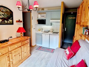 Eine kleine Küche mit Mikrowelle, Wasserkocher und Toaster. Man sieht einen Holzschrank und eine rote Lampe.