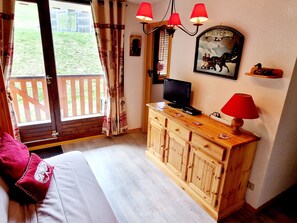 A bedroom with a wooden dresser, a television, and a painting of a horse on the wall.