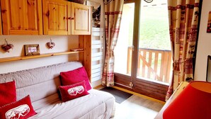 A cozy living room with a sofa, wooden cabinets, and a view of the outdoors. - Charming cabin studio near slopes in La Plagne Montalbert (La Plagne Montalbert)