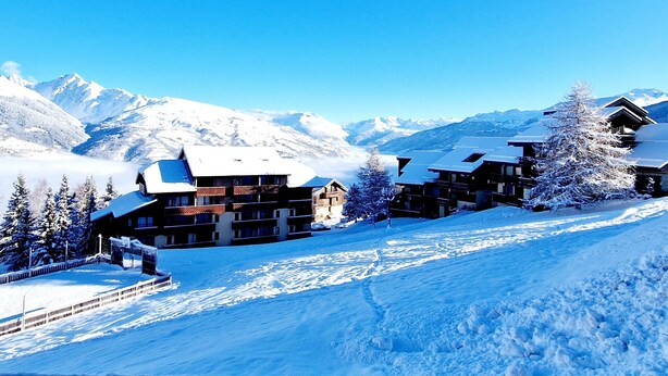 A snow-covered lodge with multiple buildings, a ski slope, and snow-covered mountains in the background. - Charming cabin studio near slopes in La Plagne Montalbert (La Plagne Montalbert)