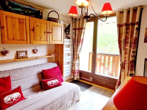 Un salon chaleureux avec un canapé, des meubles en bois et une vue sur l’extérieur.