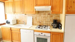 Una cuina amb armaris de fusta, microones, rentatrelle, fogó de gas, cafetera i rentavaixelles.