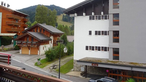 Un edifici modern amb un rètol que diu "Plein Sud" i un edifici tradicional d'estil xalet a prop.