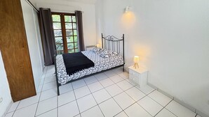 Une chambre à coucher avec un lit, une table de chevet, une fenêtre et une porte.