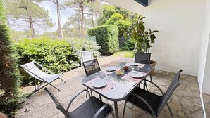 Une terrasse extérieure avec une table dressée pour quatre personnes, entourée de verdure et offrant une vue sur les arbres.