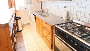 Une cuisine avec des armoires en bois, un évier en acier inoxydable, une cuisinière et un lave-vaisselle.