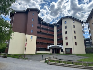 Kerrostalo, jossa on useita kerroksia, keskeinen sisäänkäynti ja parvekkeet.