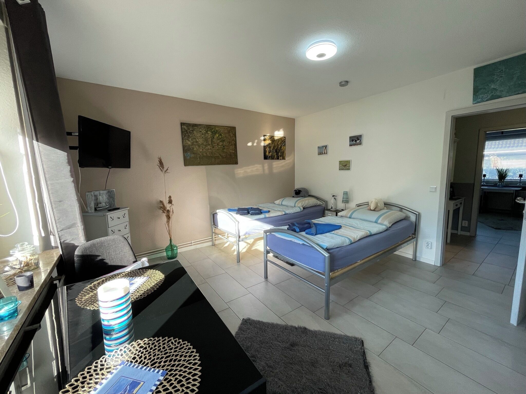 Ett hotellrum med två sängar, ett skrivbord med en stol, en TV och ett litet köksutrymme.