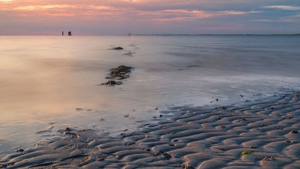 Una playa con un mar tranquilo y un cielo al atardecer.