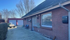 A brick house with a garage, a covered patio area, and a clear sky.
