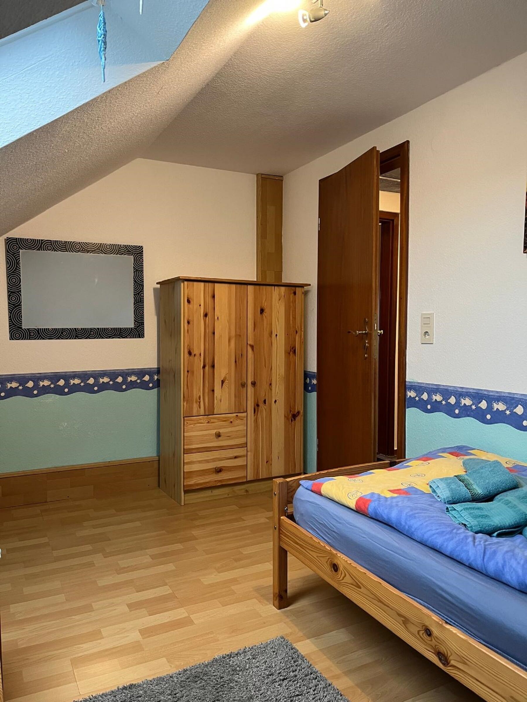 A bedroom with a wooden bed, a wardrobe, and a door leading to another room.
