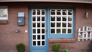 A blue door with white windows, a mailbox, and two potted plants.