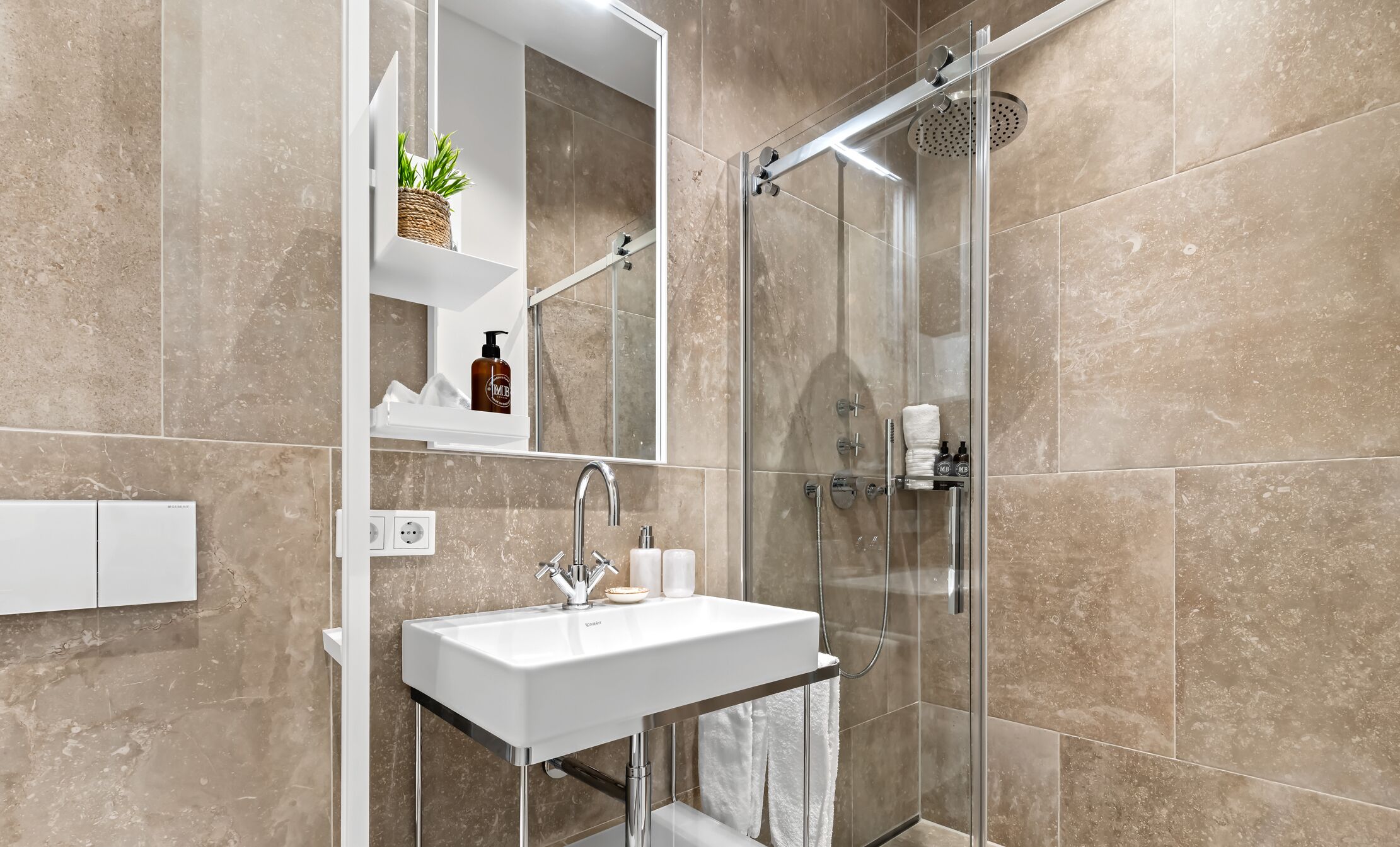 Une salle de bain moderne avec une douche à parois de verre, un lavabo blanc et un miroir au-dessus.