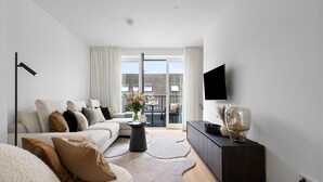 Un salon moderne avec un canapé, une table basse, un téléviseur et un balcon offrant une vue agréable.
