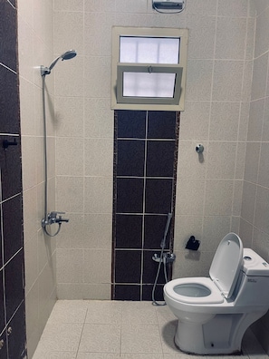 Bathroom features a shower area, toilet, and small window.