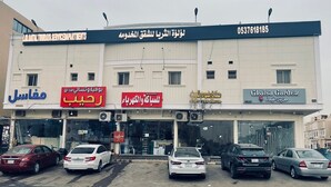 Ein Gebäude mit mehreren Läden, darunter eine Werkstatt, ein Friseursalon und ein Gartencenter.