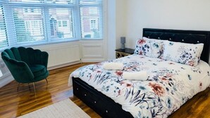 Une chambre à coucher comprenant un lit, une chaise, une table de chevet et une fenêtre avec des stores.