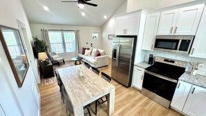 A modern kitchen with white cabinets, stainless steel appliances, and a dining area with a wooden table and chairs.