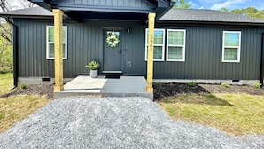 A two-story house with a dark gray exterior, a front porch with wooden posts, and a front door with a wreath.