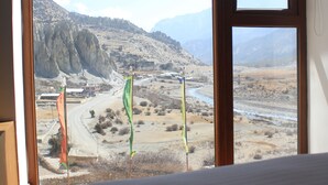 Habitació amb una finestra gran amb vista a un paisatge de muntanya.
