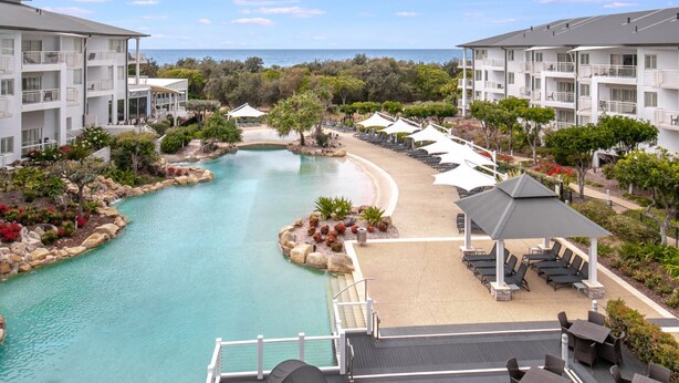 Ein Resort mit Swimmingpool, Liegestühlen und Meerblick.