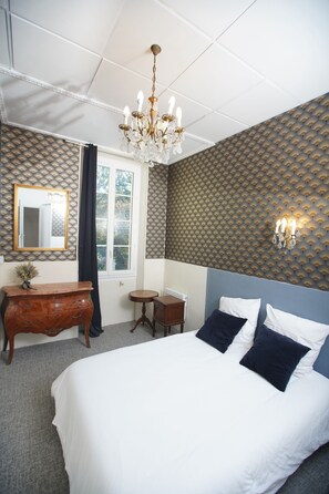 Une chambre à coucher avec un grand lit, une commode, un miroir, un lustre et un mur orné de motifs.