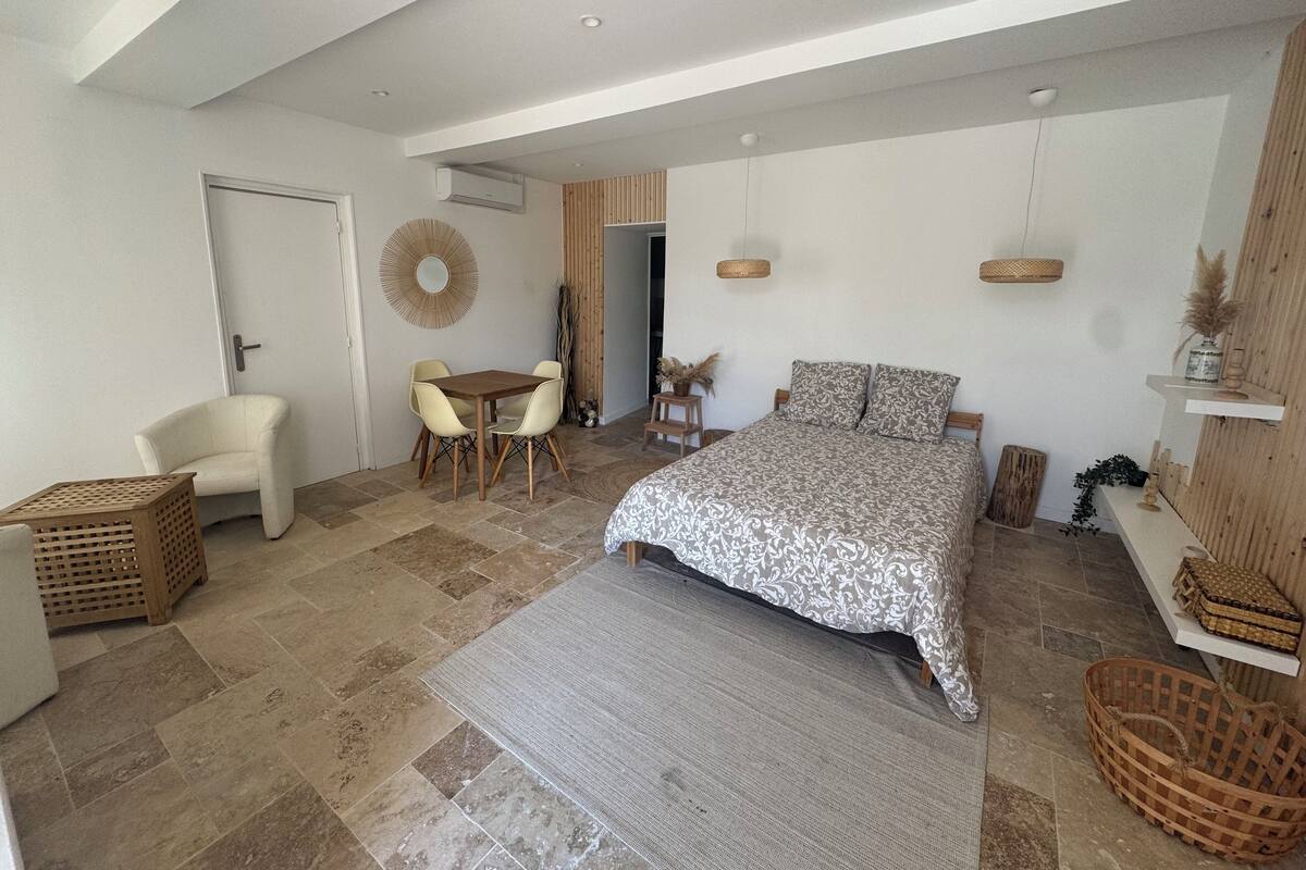 A spacious bedroom with a large bed, a sitting area with a table and chairs, a door, and a small balcony.