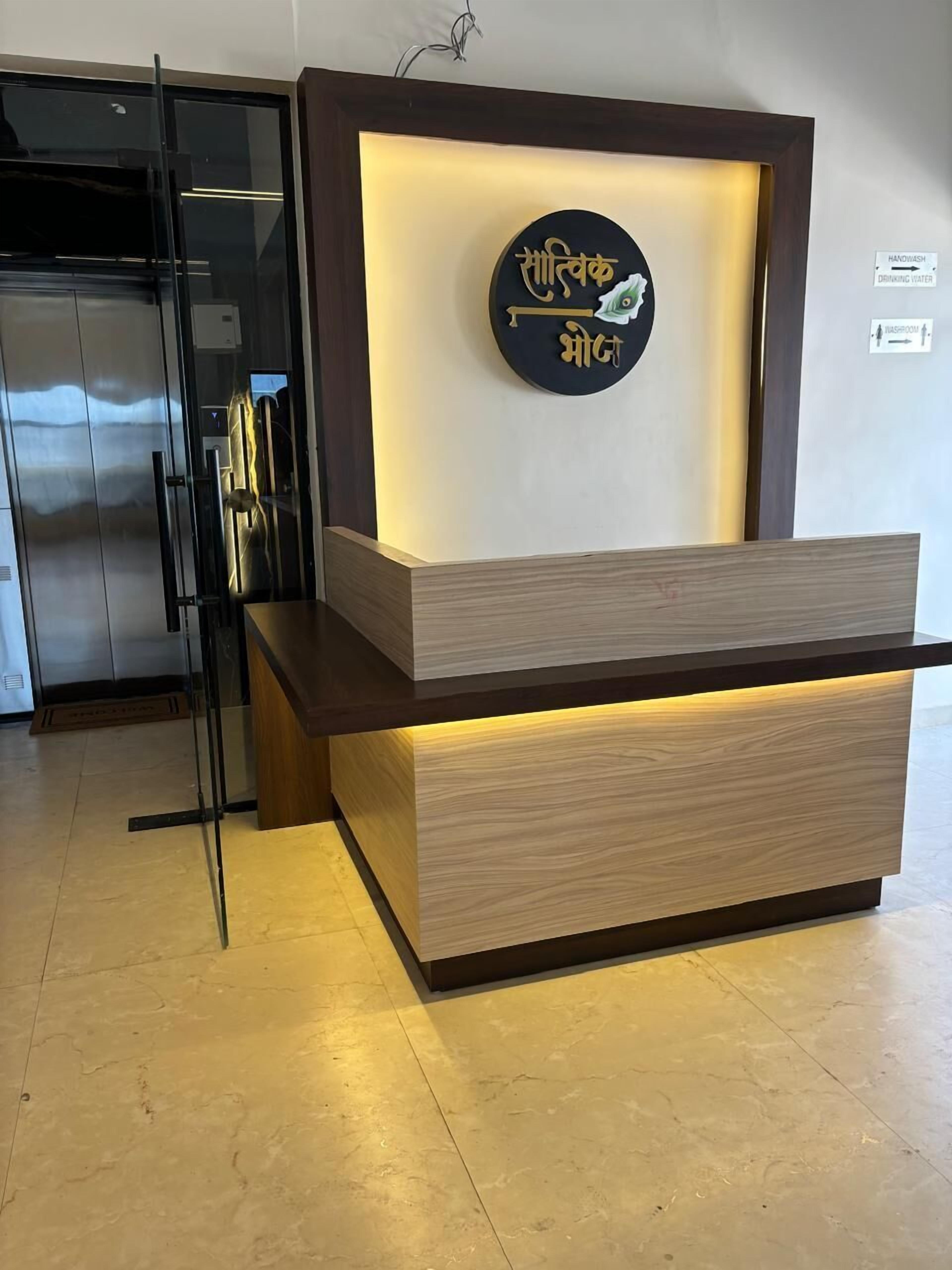 A reception desk with a wooden finish and a glass partition.