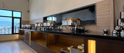 A modern kitchen with a long counter, stainless steel appliances, and a view of the city.