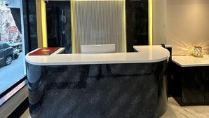 A modern reception desk with a black marble top, a white counter, and a vertical panel with a yellow accent. - Shri Bhagwan Gopi Dham Dharmsala (Haridwar)