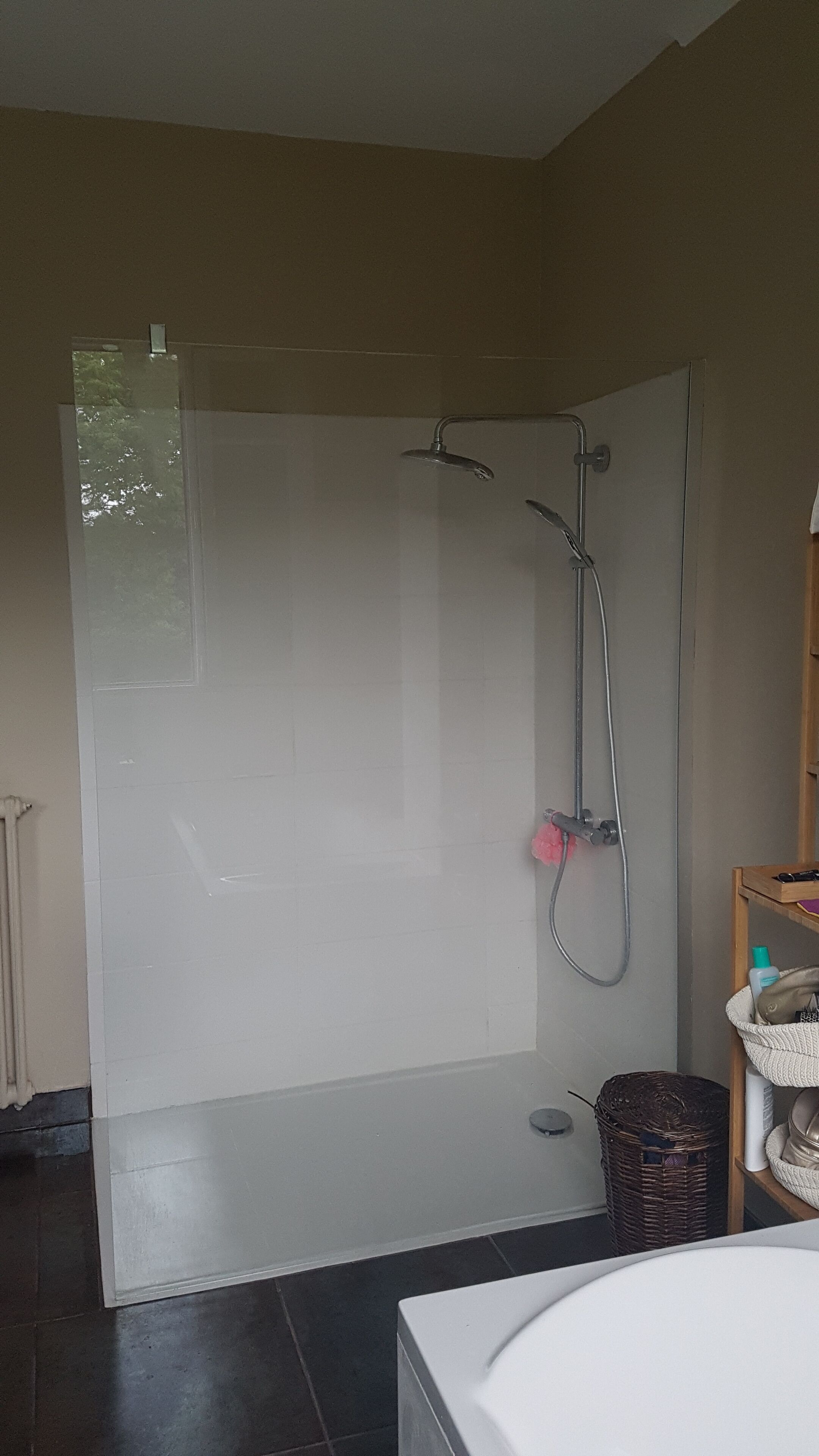 A shower with a glass door, a handheld showerhead, and a wall-mounted faucet.