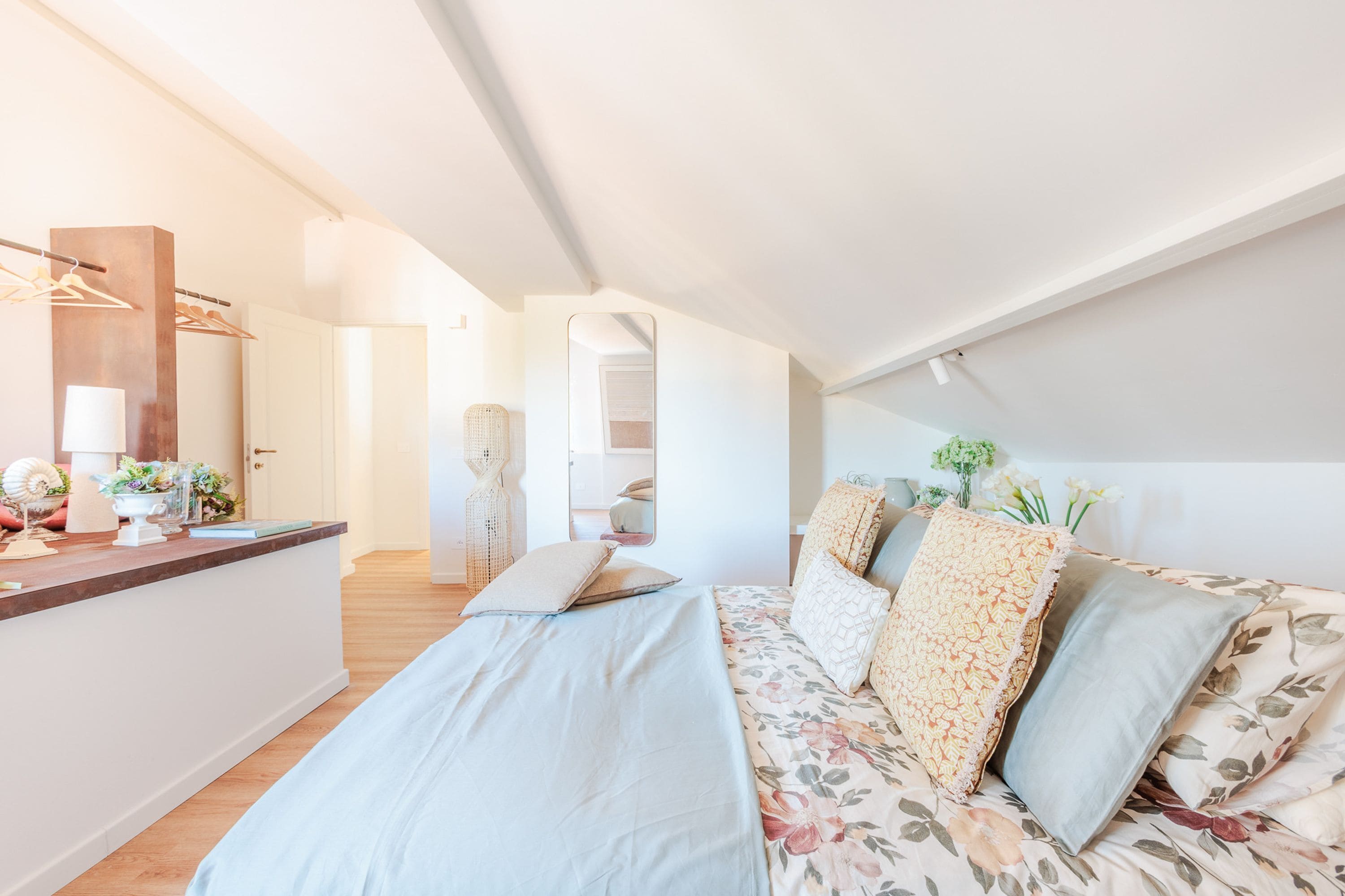Un dormitorio con cama, cómoda, espejo y puerta que da a otra habitación.