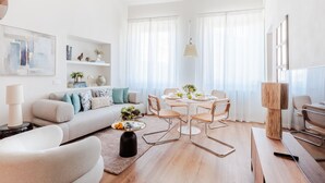A modern living room with a sofa, coffee table, and dining area. - Letizia Penthouse in Lucca (Lucca)