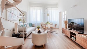 A modern living room with a spiral staircase, a dining area, and a flat-screen TV. - Letizia Penthouse in Lucca (Lucca)