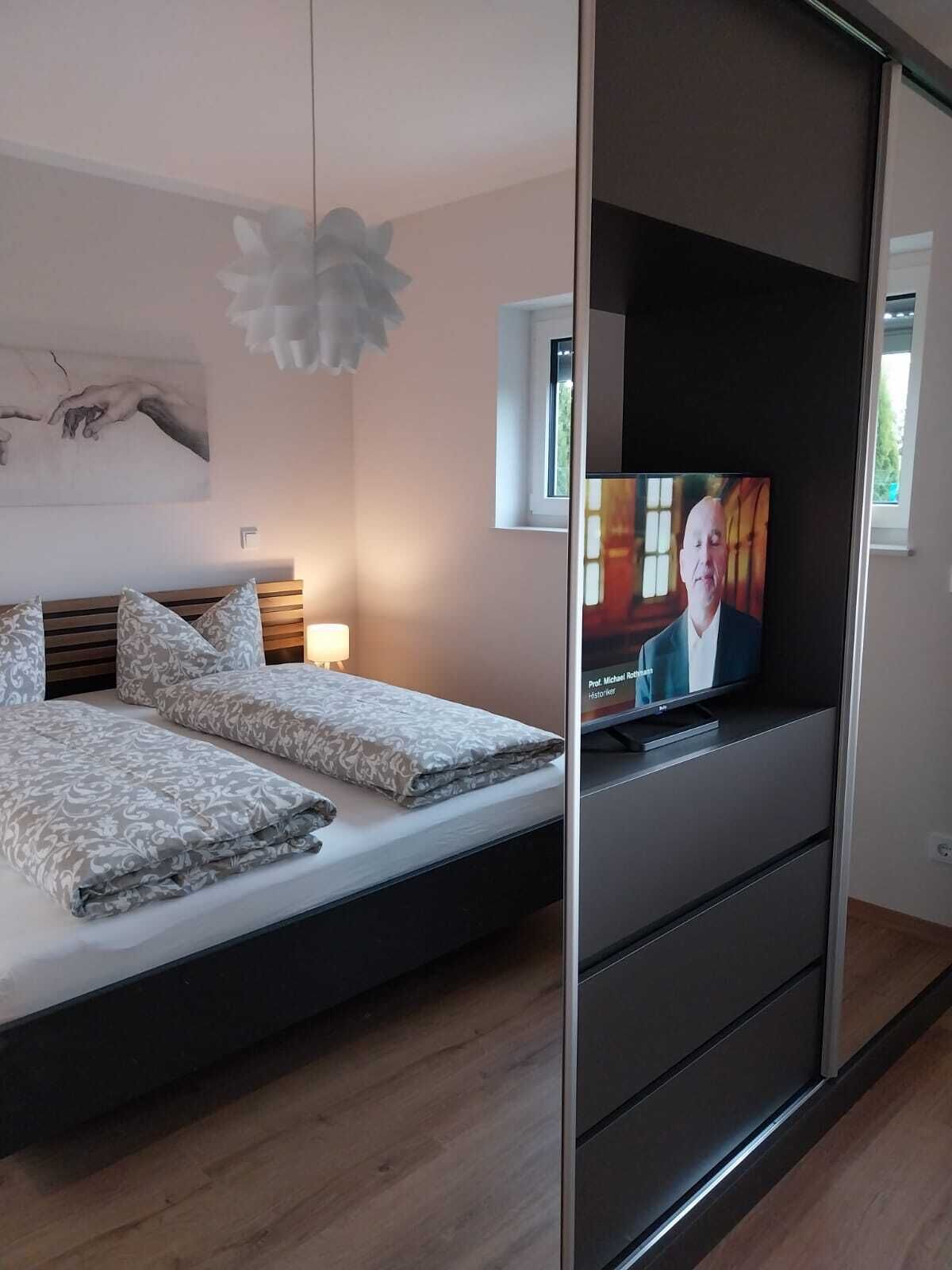 Ein modernes Schlafzimmer mit einem Bett, einem Fernseher und einer Schiebetür.