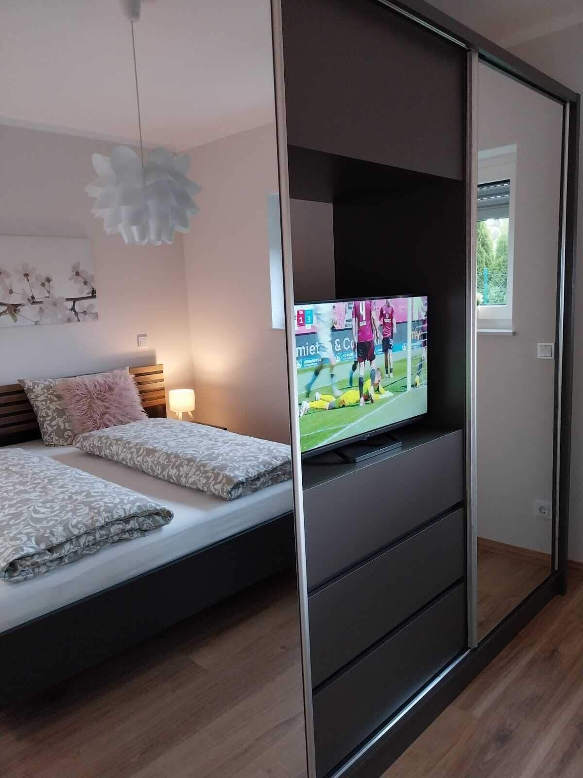 A modern bedroom with a bed, a TV, and a sliding door.