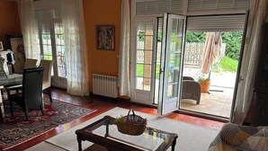 Un salon comprenant une table en verre, un panier en osier, un canapé et un coin repas avec des chaises et une table.